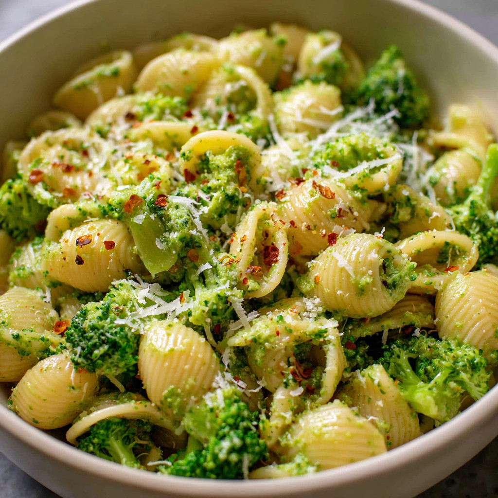 A bowl of pasta with broccoli and cheese.
