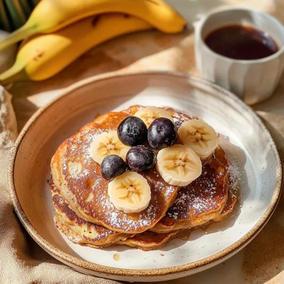 A plate of pancakes with bananas and blueberries.