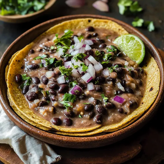 A bowl of beans with onions and lime.