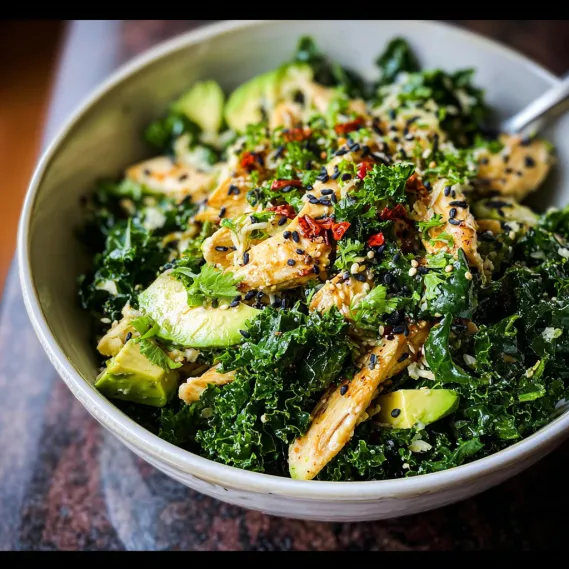 A bowl of food with chicken, avocado, and black sesame seeds.